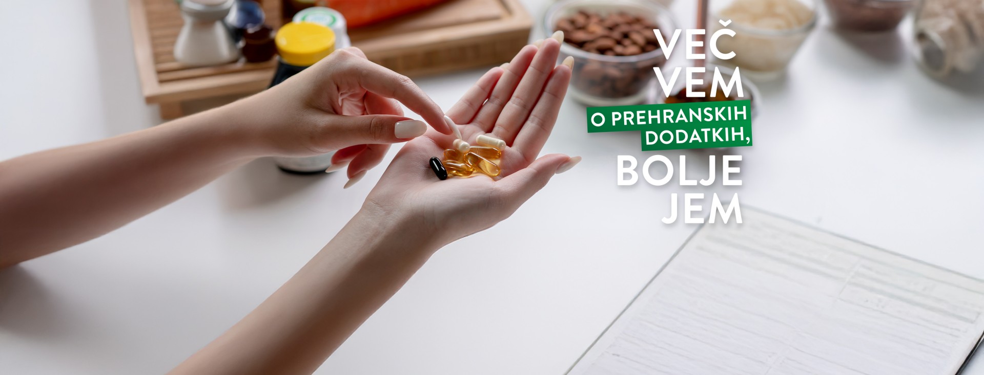 Kapsule prehranskih dopolnil v ženskih rokah, slogan VEČ VEM O PREHRANSKIH DODATKIH, BOLJE JEM