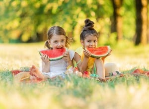 Dve punčki jesta lubenico na pikniku