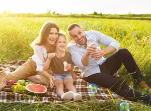 Družina na pikniku na travniku, pihanje milnih mehurčkov