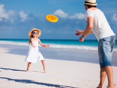 Oče in hčerka med igro s frizbijem na peščeni plaži