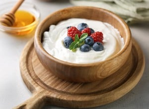 Skyr v leseni posodi z borovnicami in malinami ter medom