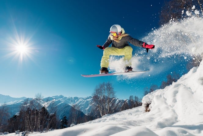 Girl is jumping with snowboard from the hill