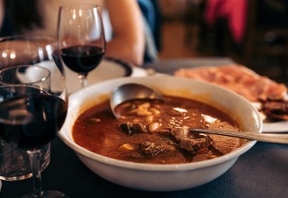 Krožnik golaža in kozarca rdečega vina