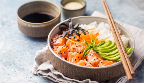 Hawaiian salmon poke bowl with seaweed, avocado, carrot, sesame seeds and rice.