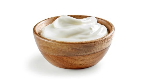 Jogurt v lesenem lončku na beli podlagi