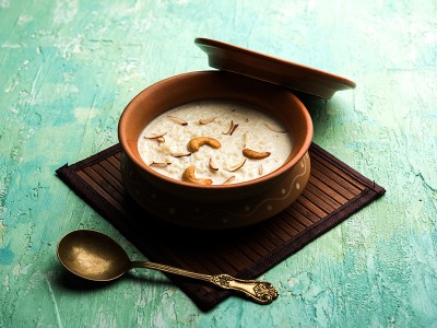 Indijska jed Kheer v glineni posodi na turkizni podlagi