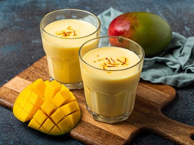 Mango lassi v kozarcu, zraven sveže narezan mango