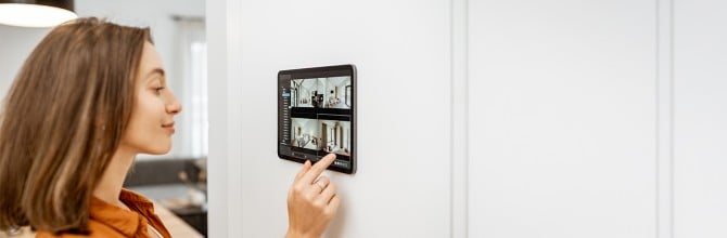 Mlada ženska doma gleda videoposnetke z varnostnih kamer na pametnem nadzornem sistemu