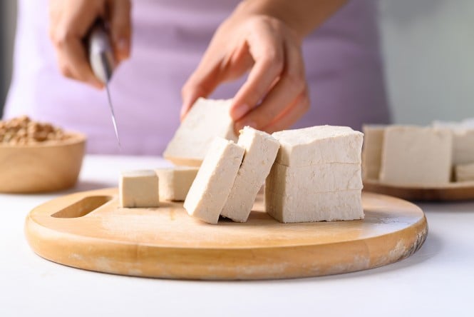 Ženska reže tofu na leseni deski