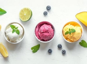 Limonin, borovničev in mangov sladoled v lončkih na svetlem ozadju, fotografiran iz ptičje perspektive