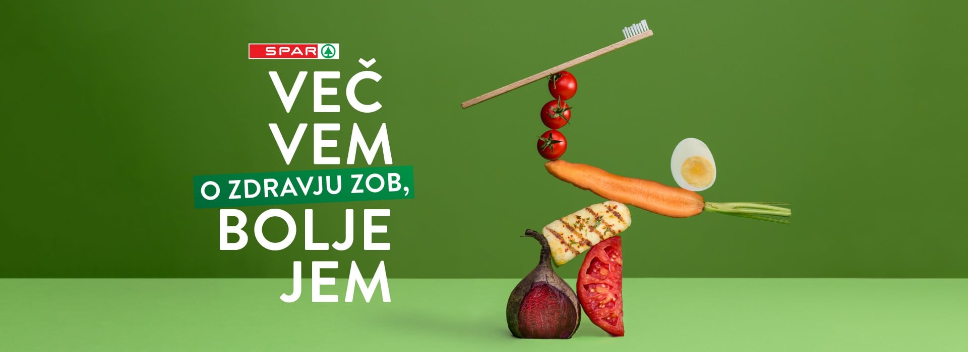 Slogan Več vem o zdravju zob, bolje jem in zloženka živil na zeleni podlagi