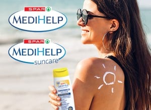 SPAR MEDIHELP in SPAR MEDIHELP suncare, ženska ob morju s kremo SPAR MEDIHELP suncare kremo  v rokah