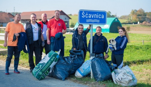 Skupina ljudi zraven znaka Ščavnica z vrečami smeti