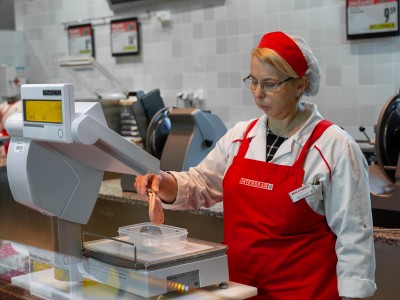 Prodajalka v embalažo naloži želeno živilo.