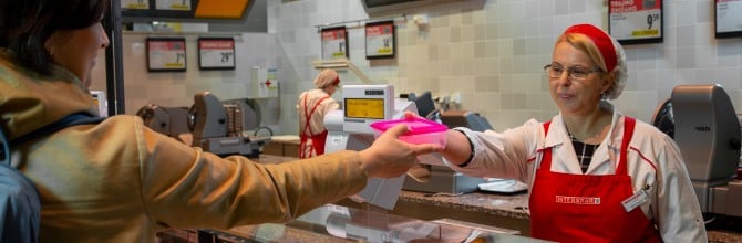 Kupec prodajalki ponudi prazno embalažo.